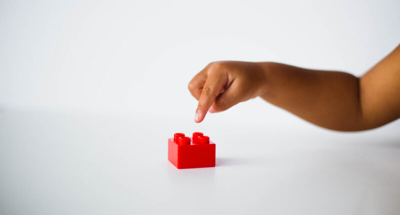 Child pointing to a lego block